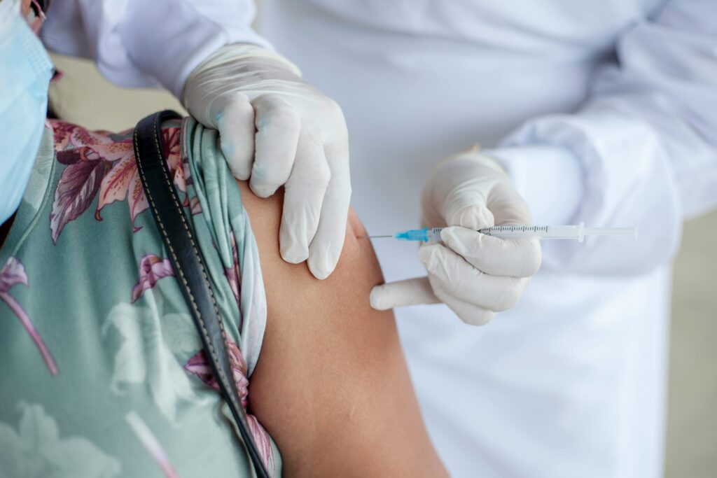 Close-up of a healthcare professional giving a vaccine shot to a patient wearing a mask.